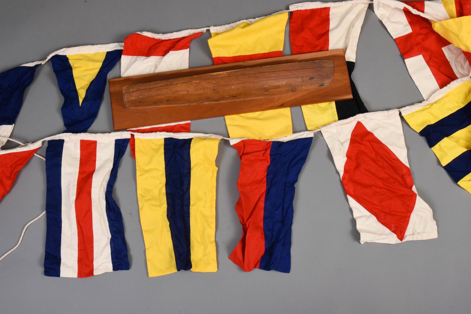 Maritime Signal Flags and a Small Half Hull Model.: The model of lift construction wtih four lifts, back board 26 x 5.75 inches. Total length of signal flags approximately 28 feet.