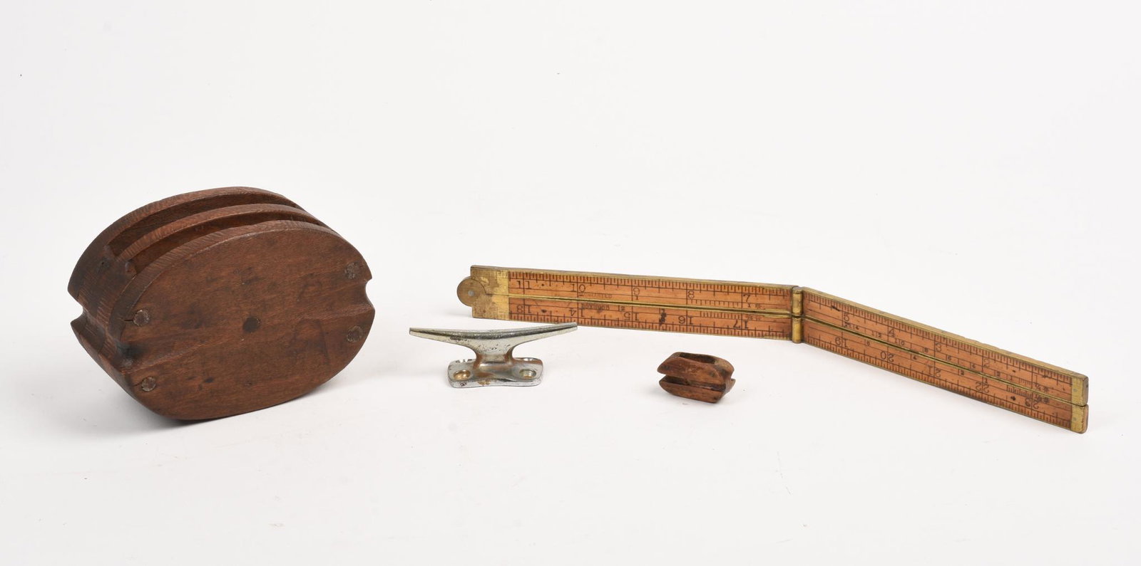 Group of Small Nautical Items.: A pulley, length 4.75 inches, miniature pulley, folding rule, and a miniature cleat.