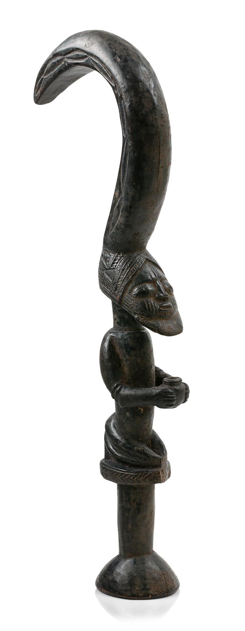 Yoruba Male Eshu Ceremonial Staff: With extended hook from head with second face on end of hook signifying duality of Eshu deity. Male is holding a pot. 18"H