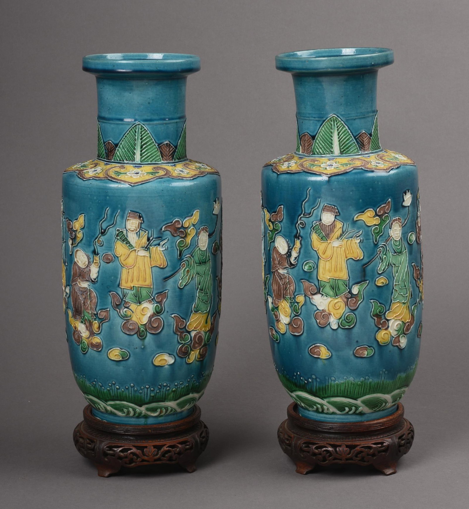 Pair of Chinese Wang Binrong Type Porcelain Vases: With scenes depicting luohans floating on clouds on a blue ground, Wang Binrong marks, carved wooden stands, late 19th century, height without stand 11.5 inches
