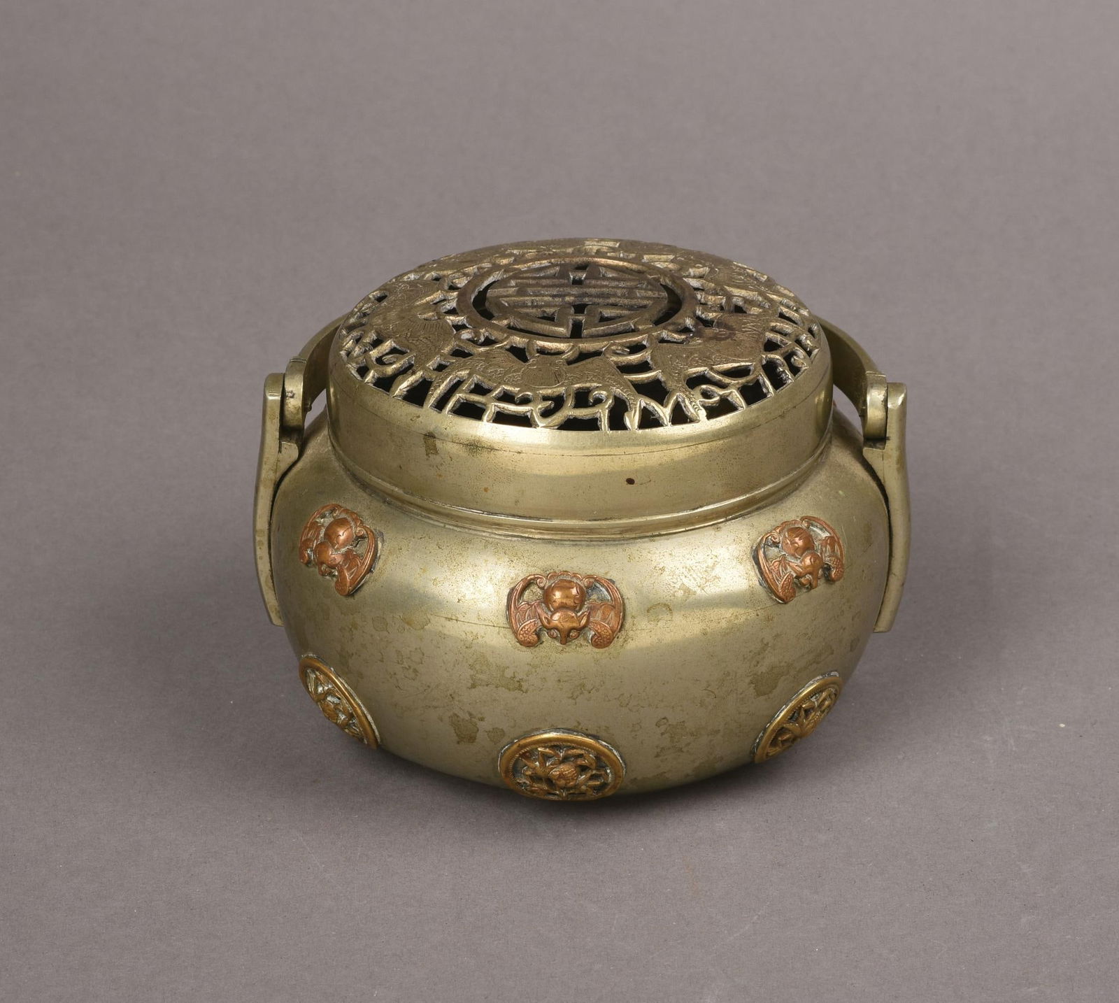 Chinese Paktong Hand Warmer: With 6 applied gilt copper roundels of plants, 6 applied gilt copper bats, the cover decorated with a Shou character and 5 bats, 19th century, height 4.25 inches, minor dents