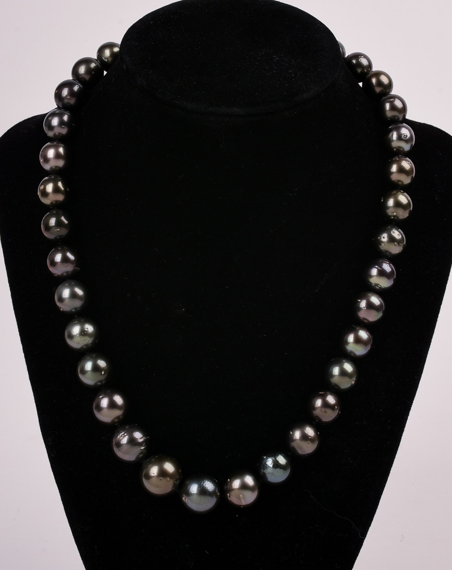 Tahitian Pearl Necklace: Length 18.5 inches, graduated single strand cultured Tahitian pearl necklace. Hand knotted 14K white gold plunger style tension locking clasp. 35 pearls measuring 11.06-13.96mm. Gross weight 91.13 Gra