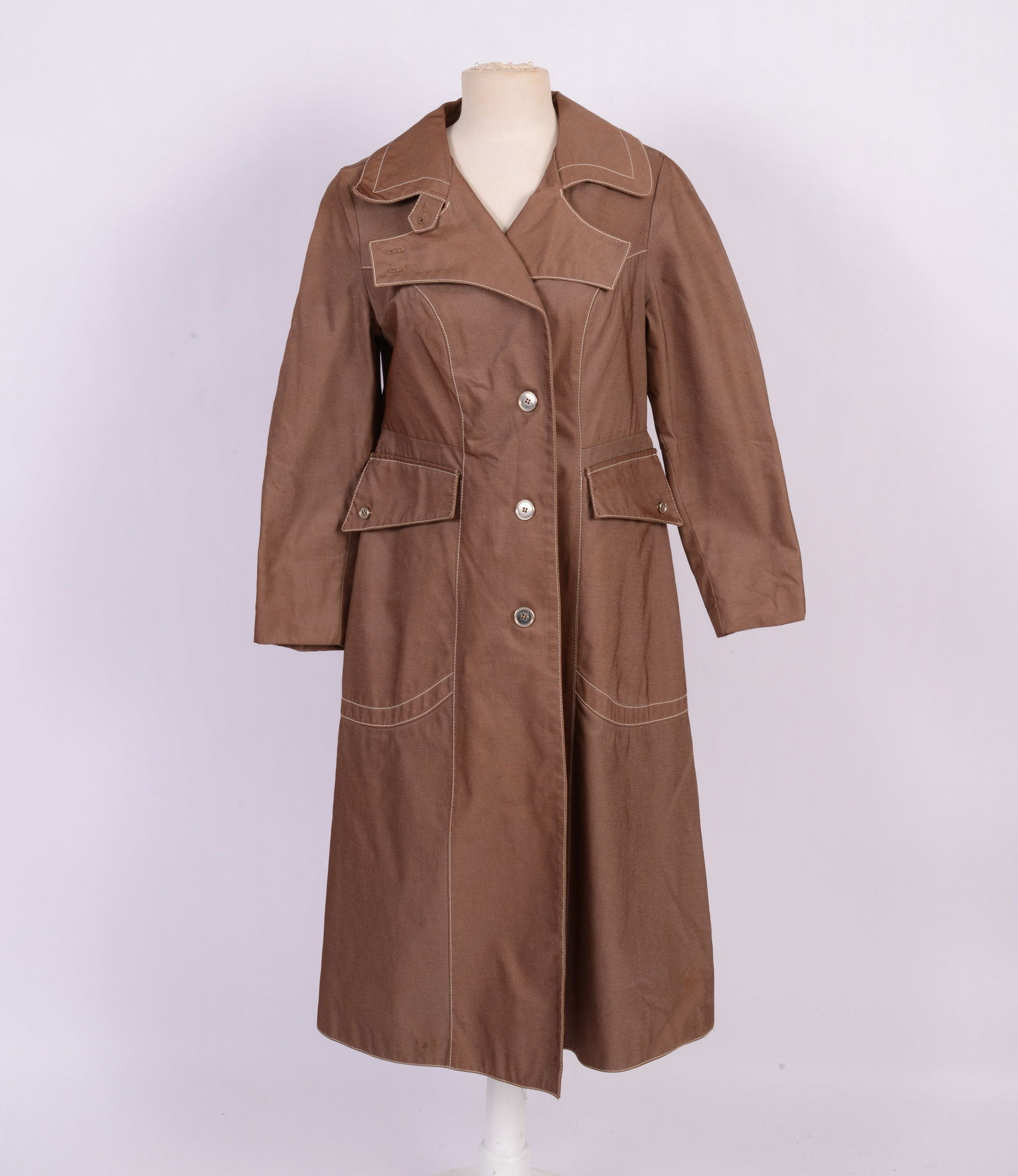 Long Tan Trench Coat Made in Finland: Size 40, with white stitched trim, large front pockets, back slit and 4 button closure, length 44 inches, good condition.