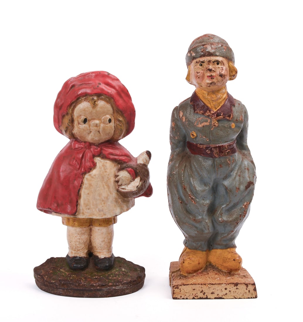 TWO CAST IRON DOORSTOPS.: One as Red Riding Hood, and the other in a uniform-like outfit. Height of taller 11 1/8 inches, width 3.5 inches. Both with varying degrees of paint chipping. IN HOUSE SHIPPING: We offer very competit