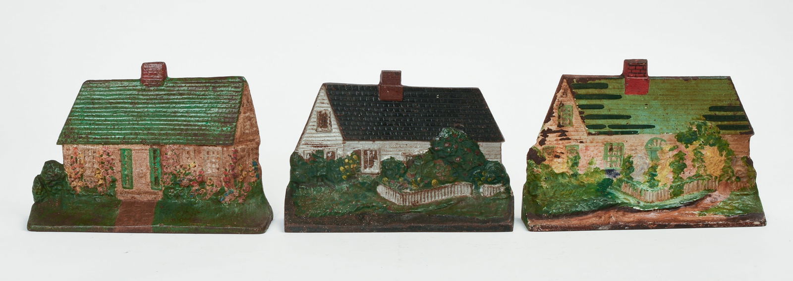 THREE CAST IRON HOUSE DOORSTOPS.: Two with green roofs, one with black roof. Light green roof house stamped on back "Eastern Specialty MFG CO/ 14." Dark green roof house stamped "90" on back. Height of light green roof house to top of