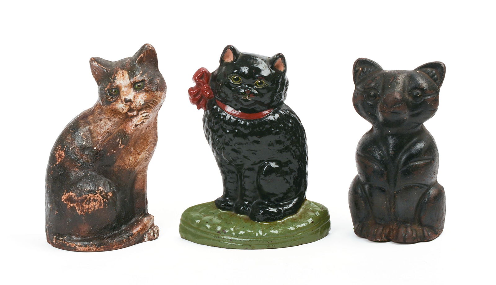 THREE CAST IRON CAT DOORSTOPS.: All dark or black paint. Black cat with red bow has "87" stamped on back with handwritten "L. Eaton" in green paint. Two-tone cat stamped on back, "Copyright 1926/ Waverly Studio/ Wilmette - ILL." Hei