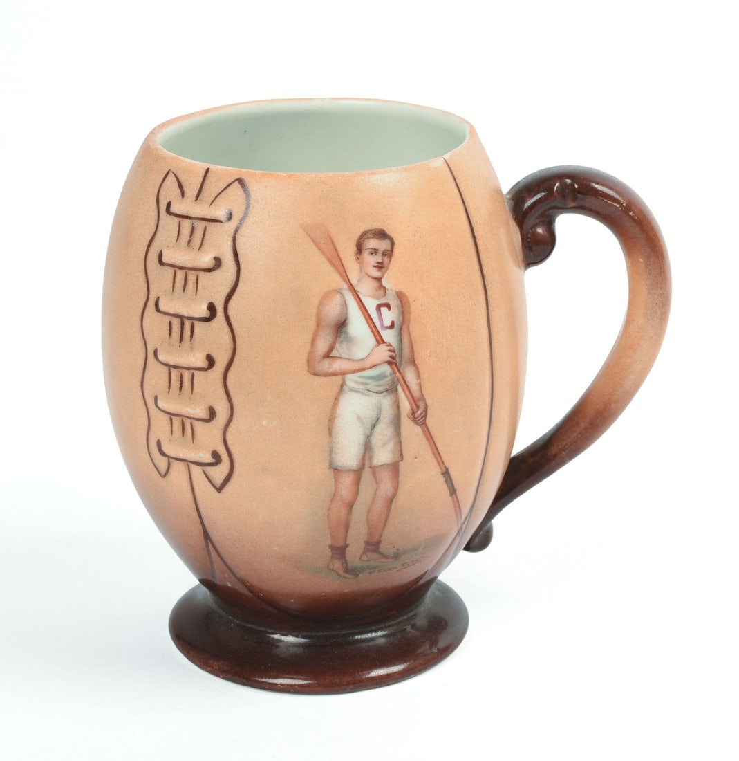 Handpainted Cornell University Football Shaped Mug: Decorated on one side with a uniformed rower, 1905, T. Maddockâ€™s Sonâ€™s, Trenton, N.J., signed F. Earl Christy. Height 5 inches.