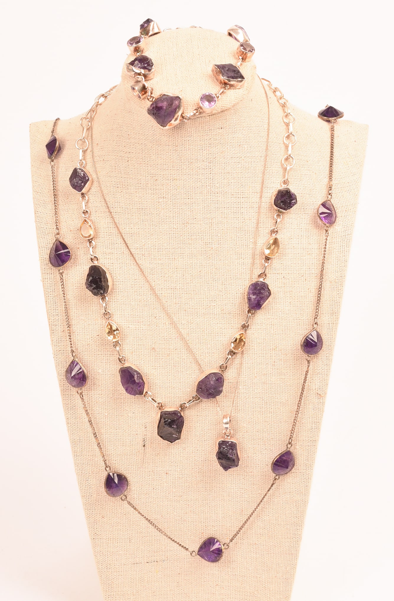 Three Amethyst Necklaces and a Bracelet.: Longest necklace 17 inches. Stand included.
