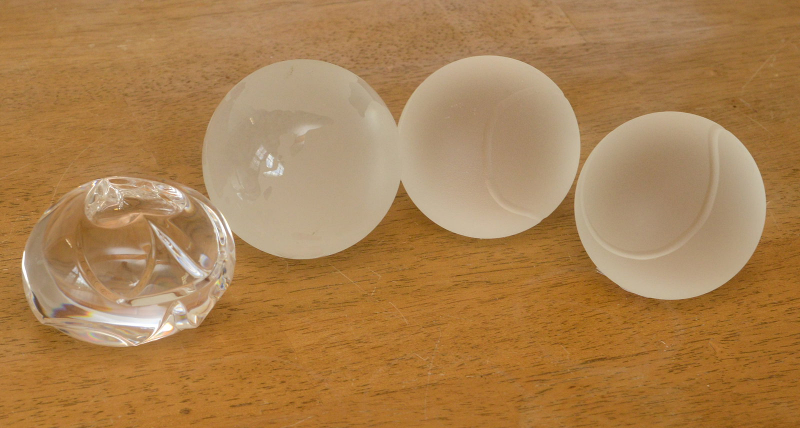 Four Glass Paperweights.: Two Tiffany & Co tennis balls, diameter 2.75 inches, Steuben, and one unmarked.