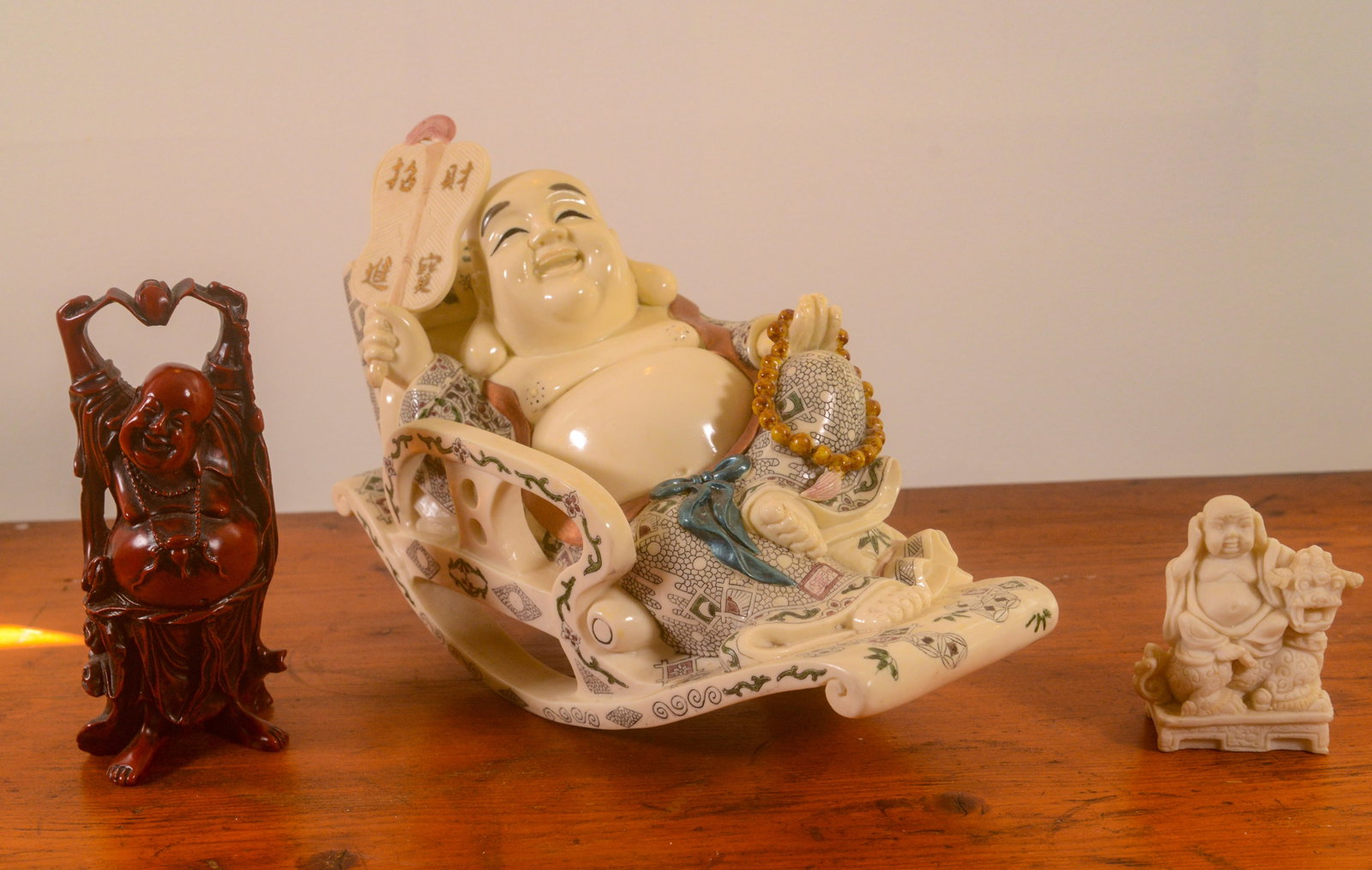 Three Chinese Resin Figures.: Buddha in a rocking chair, length 12 inches, and two others.