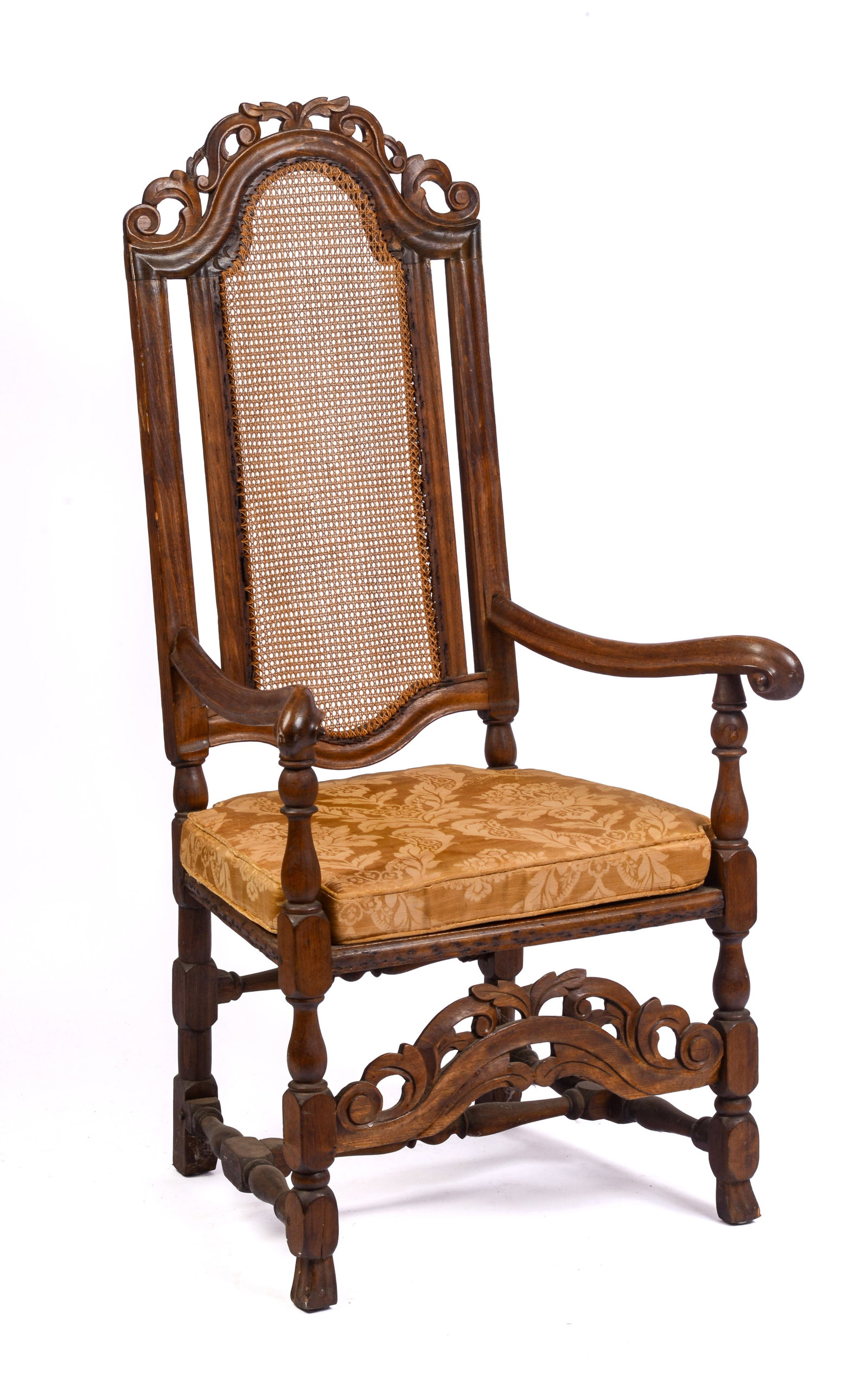 JACOBEAN CANE BACK ARMCHAIR.: With scrolled arms and carved crest, circa 1690. Seat height 15.5 inches, overall height 44 inches, width 23 inches, depth 17 inches.