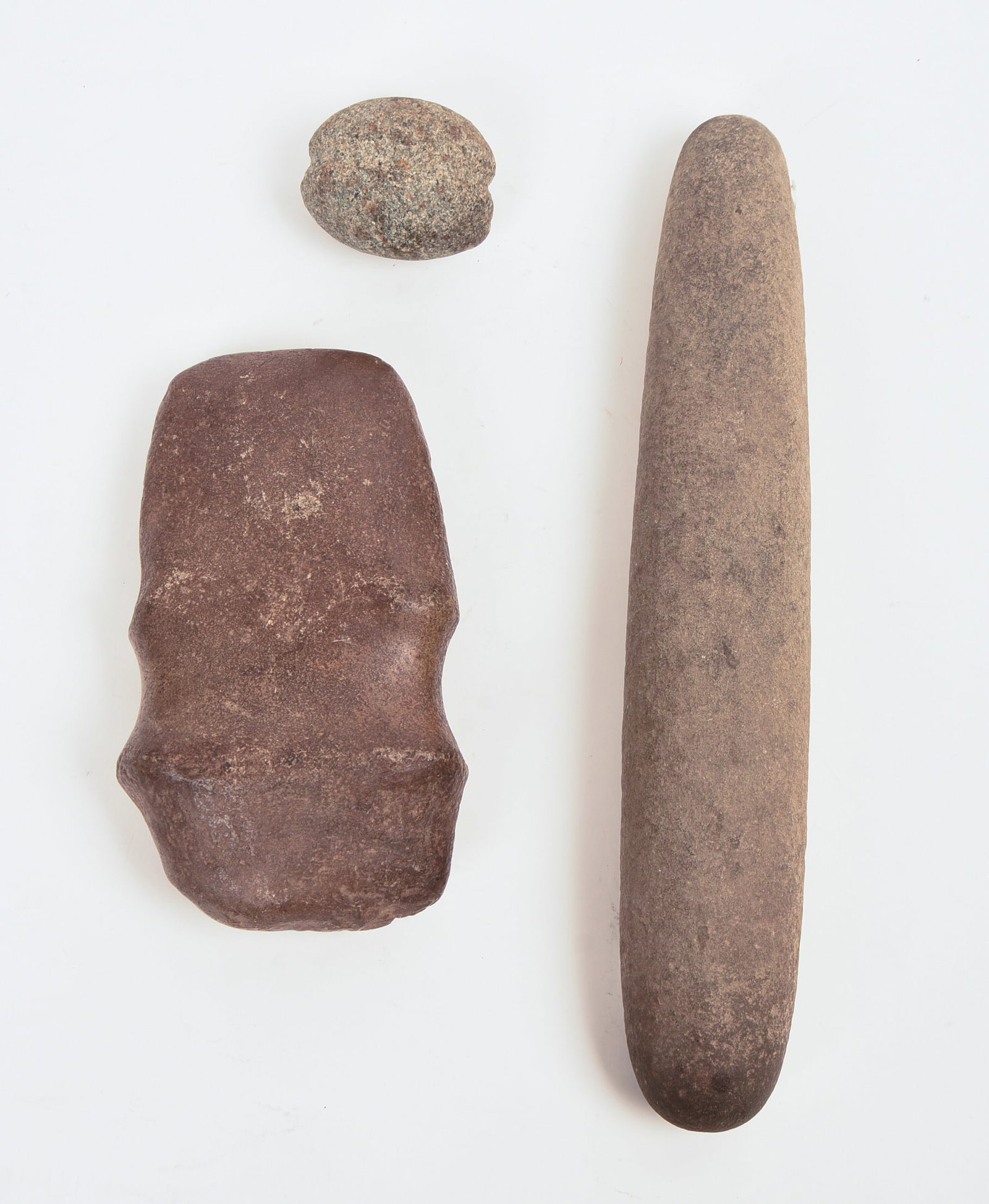 THREE NATIVE AMERICAN STONE TOOLS.: Rolling pin, length 13.5 inches; axe head, 8 x 4 inches; small hammer head.