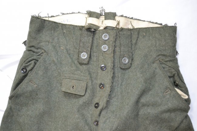 WWII GERMAN ARMY M43 FIELD UNIFORM TROUSERS: WWII GERMAN ARMY M43 FIELD UNIFORM TROUSERS . HEAVY WOOL FIELD GREEN COARSE TEXTURE . WELL WORN . RUSSIAN CAPTURED AND WORN .ORIGINAL GERMAN INK ISSUE STAMPS DATED 1944 AS WELL AS RUSSIAN OWNERS NAMES