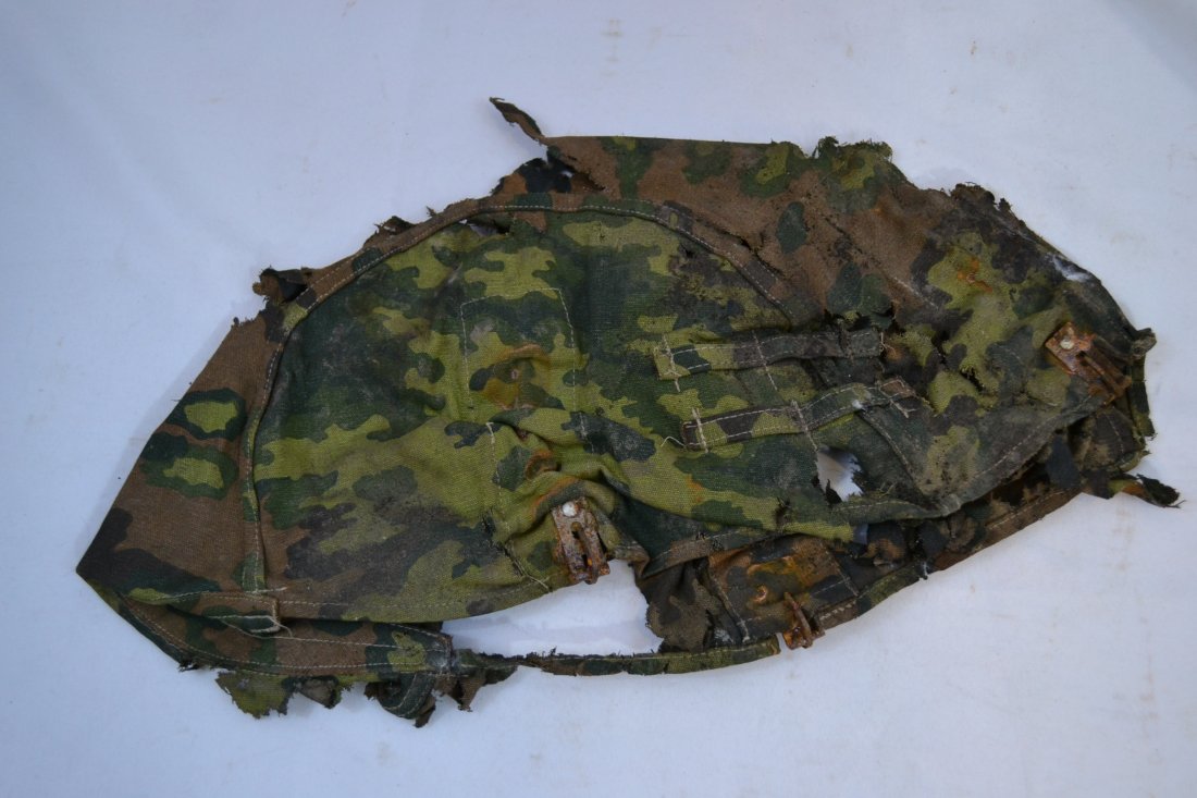 WWII GERMAN WAFFEN SS CAMOUFLAGE CLOTH HELMET COVER: WWII GERMAN WAFFEN SS CAMOUFLAGE CLOTH HELMET COVER . RELIC CONDITION . MUCH WEAR , TEARS AND HOLES . CONSIGNER STATED IT WAS FOUND IN THE ATTIC OF AN OLD HOUSE IN LATVIAN VILLAGE. THE METAL CLIPS ARE