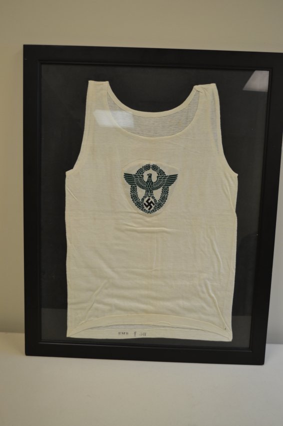 WWII NAZI POLICE SPORT SHIRT WITH INSIGNIA FRAMED: WWII NAZI POLICE SPORT SHIRT WITH INSIGNIA FRAMED . NICE MINTY CONDITION ORIGINAL WHITE POLICE SPORT SHIRT . INK STAMPED INSIDE . MOUNTED ON THE NICE DISPLAY FRAME WITH GLASS . READY TO DISPLAY ON THE