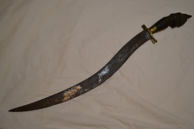 ANTIQUE NORTH AFRICAN UNIQUE CURVED BLADE SWORD: ANTIQUE NORTH AFRICAN UNIQUE CURVED BLADE SWORD WITH DECORATIVE HANDLE GRIP. DISPLAYS A GREAT AGE . 28" LONG WITH 20" BLADE. BRASS CROSS GUARD. BLADE HAS ENGRAVED "NERGITO BOLO" .VERY UNIQUE WEAPON.
