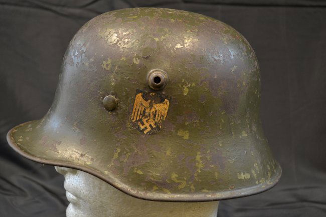 WWII GERMAN TRANSITIONAL HELMET M18 WITH LINER / DECAL: WWII GERMAN TRANSITIONAL HELMET . ORIGINALLY M18 GERMAN WWI MADE HELMET . REPAINTED WITH GREEN GRAY PAINT WITH SINGLE EAGLE DECAL REMAINING. M35 LINER . WELL WORN EXAMPLE. SMALL SIZE
