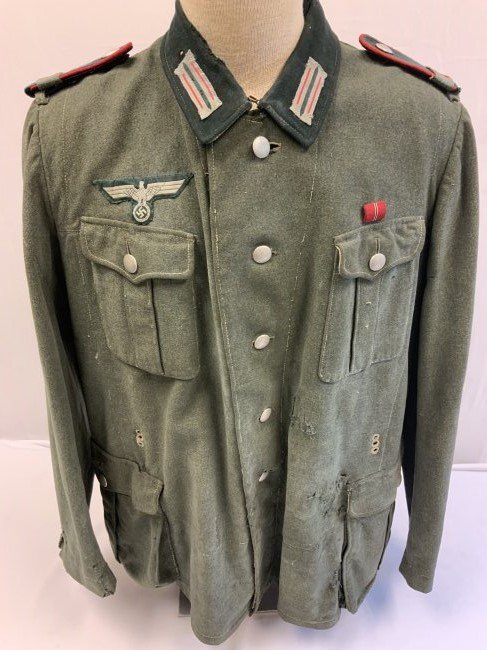 WWII GERMAN ARTILLERY ENLISTED FIELD UNIFORM TUNIC: WWII GERMAN ARTILLERY ENLISTED FIELD UNIFORM TUNIC . WELL WORN EXAMPLE. DISPLAYS MUCH WEAR WITH STAINS, HOLES AND REPAIRS. SLIDERS ON SHOULDER BOARDS WITH 72nd REGIMENT . NICE LARGE SIZE. INK STAMPED 