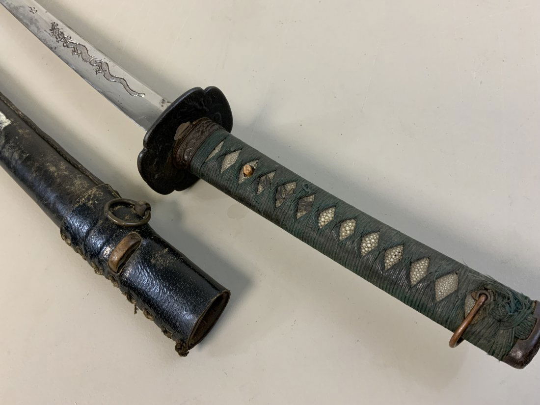 ANTIQUE JAPANESE SAMURAI SWORD SIGNED HORIMONO DRAGON: ANTIQUE JAPANESE SAMURAI SWORD WWII LEATHER COVERED SCABBARD.VERY OLD SWORD WITH HORIMONO DRAGON CARVING TO THE BLADE . WAVY HAMON . SIGNED TAND WITH LONG SIGNATURE . TANG DISPLAYS A GREAT AGE. ANTIQU