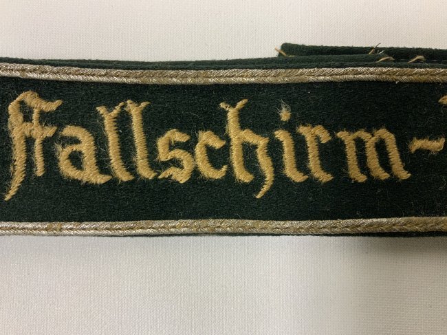 WWII GERMAN LUFTWAFFE "Fallschirm-Division" CUFFTITLE: WWII German Luftwaffe Paratrooper "Fallschirm-Division" Cuff Title. Smooth dark green wool, the exterior bearing a machine-embroidered silver-grey inscription of "FALLSCHIRM-DIVISION" Well worn used b