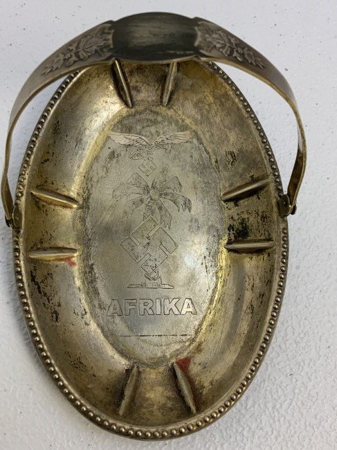 WWII GERMAN LUFTWAFFE SILVER AFRIKA CANDY OR ASHTRAY WITH HANDLE: WWII GERMAN LUFTWAFFE SILVER AFRIKA CANDY OR ASHTRAY WITH HANDLE . BEAUTIFUL ETCHING TO THE TRAY WITH LUFTWAFFE EAGLE , PALM TREE AND A WORD " AFRIKA" . SOME MARKINGS ON THE SIDE. 6.5 X 4 OVAL SIZE. G