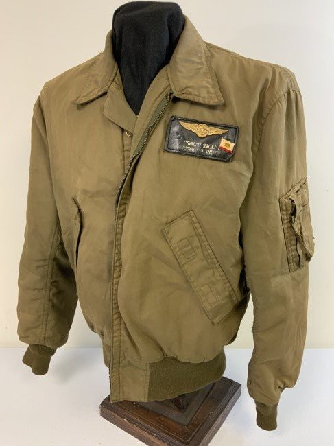 US VINTAGE VIETNAM WAR ERA CANVAS FLYING JACKET NAMED: US VINTAGE VIETNAM WAR ERA CANVAS FLYING JACKET NAMED . WELL WORN JACKET WITH FRONT ZIPPER BROKEN . NAME ON THE FRONT TAG WITH BRASS WINGS AND CALIFORNIA PIN ATTACHED . RARE FIND .