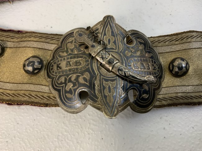 IMPERIAL RUSSIA GEORGIA SILVER DECORATED FEMALE BELT: IMPERIAL RUSSIA GEORGIA SILVER FEMALE BELT . BEAUTIFUL WORK . SILVER NIELLO FITTINGS. SIGNED BY THE SILVER SMITH UNIQUE BUCKLE WITH MINIATURE DAGGER CLOSURE . GOLD DECORATED FABRIC BELT WITH PURPLE VE