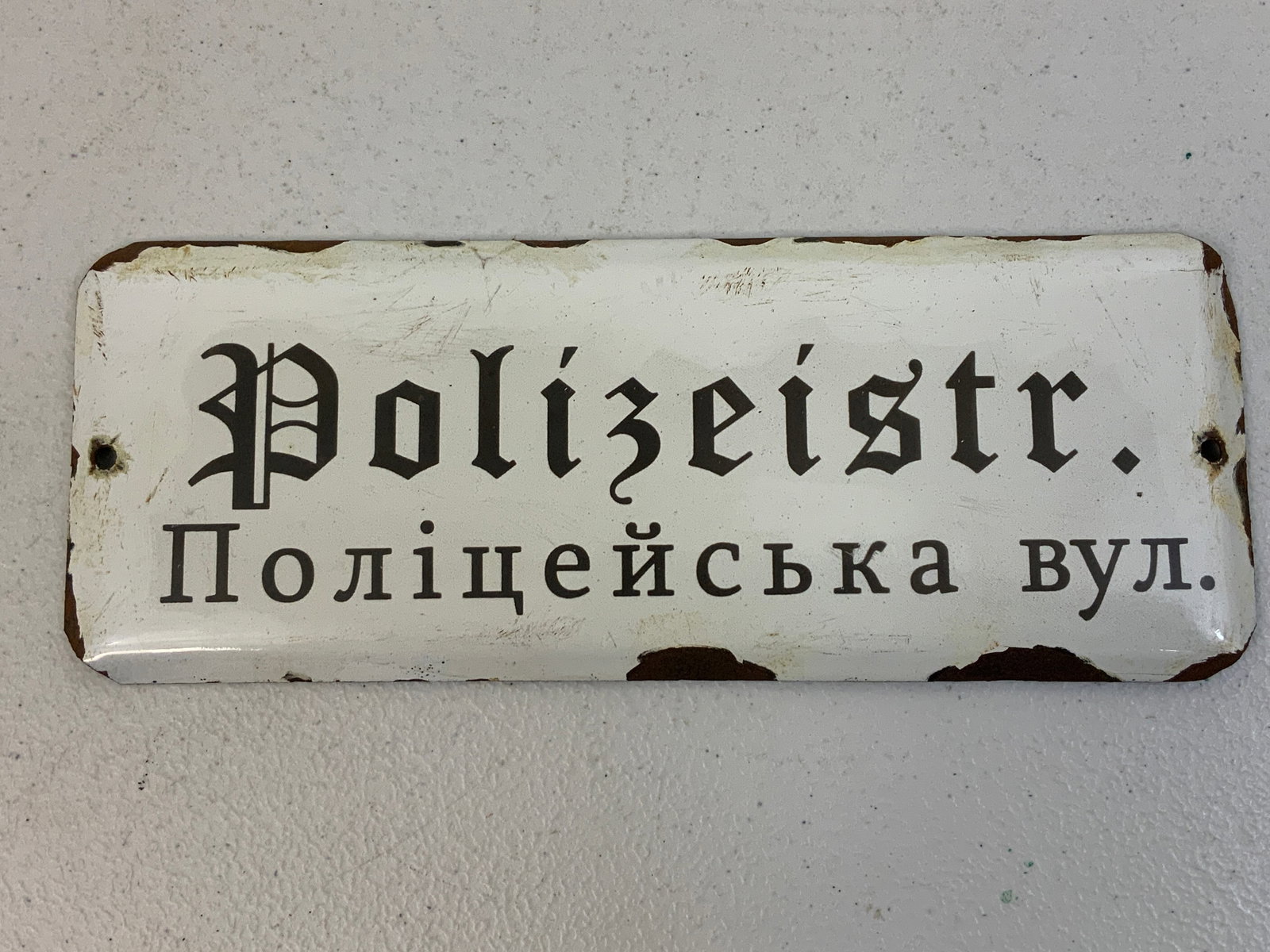 WWII NAZI GERMANY OCCUPIED UKRAINE PORCELAIN STREET SIGN: WWII NAZI GERMANY OCCUPIED UKRAINE PORCELAIN STREET SIGN . POLIZEISTR. IN GERMAN AND POLICE STREET IN UKRAINIAN. VERY RARE TO FIND. 10 X 4 SIZE. GOOD CONDITION WITH SOME CHIPS TO ENAMEL .