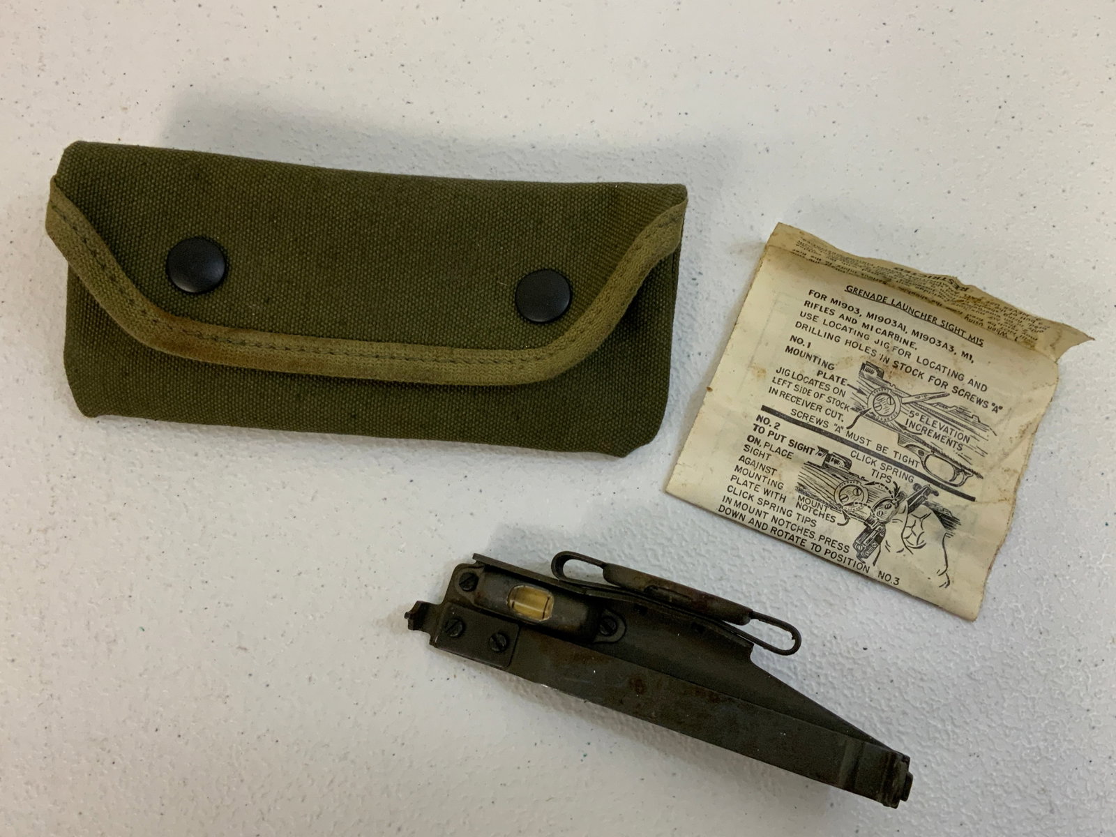 WWII US M1 GARAND CARBINE M15 GRENADE LAUNGER SIGHT IN CANVAS POUCH: US Military M15 Grenade Launcher Sights. A WW2 era item designed for use on the 1903 Springfield, M1 Garand and M1 Carbine service arms. Includes the canvas pouch 1944 dated, mounting base, sight inst