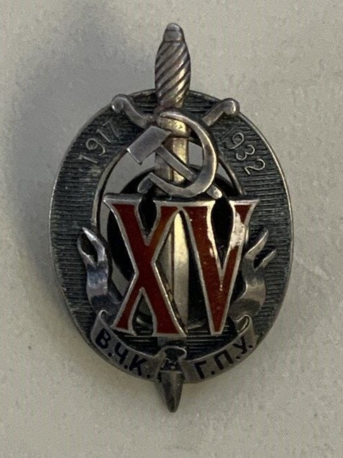SOVIET RUSSIA 1917-1922 EARLY CHEKA OGPU NKVD KGB BADGE: FIFTEEN ANNIVERSARY BREAST BADGE OF THE MERITORIOUS CHEKIST OF GPU 1917-1922 BADGE. SILVER WITH RED ENAMELED ROMAN NUMBER XV. BANNER BELOW WITH THE ABBREVIATION V.CH.K.- G.P.U. IN DARK BLUE - NEAR BLA
