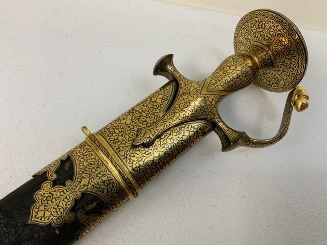 ANTIQUE INDIAN GOLD DECORATED FITTINGS TULWAR SWORD: ANTIQUE INDIAN GOLD DECORATED FITTINGS TULWAR SWORD . BEAUTIFUL PIECE. VERY NICE CONDITION . BEAUTIFUL GOLD DECORATED FITTINGS. NICE STRONG BLADE. OLD PRESSED DECORATED LEATHER ON THE SCABBARD. 37" LO