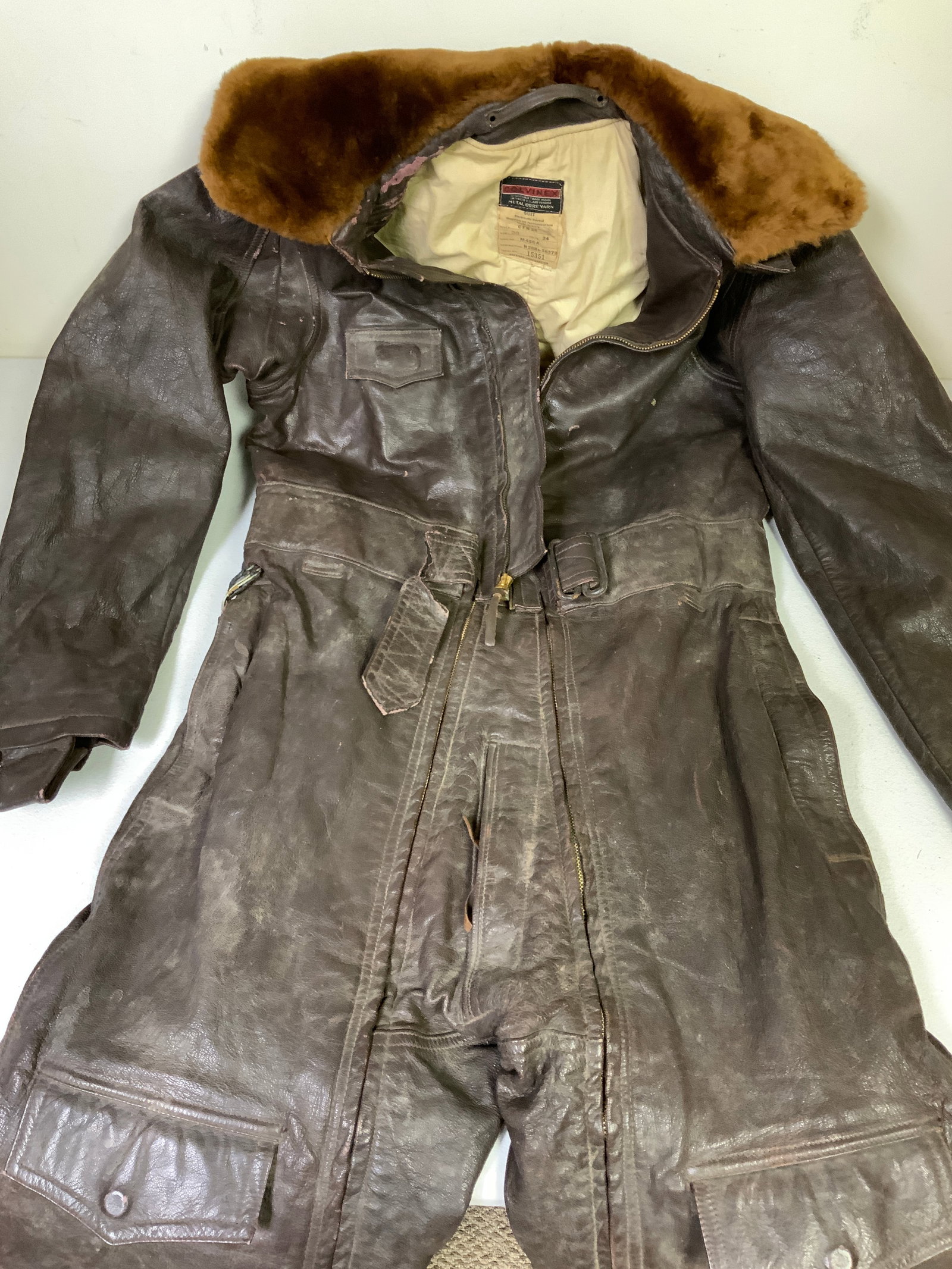WWII U.S. NAVY COLVINEX CFN-24 ELECTRICALLY HEATED LEATHER FLIGHT SUIT: WWII U.S. NAVY COLVINEX CFN-24 ELECTRICALLY HEATED LEATHER FLIGHT SUIT. BROWN LEATHER . FUR COLLAR AND COTTON LINING .TEAR IN THE WAIST BELT. WIRE INSULATION TO THE HEATING REMOTE IN THE POCKET IS FLA