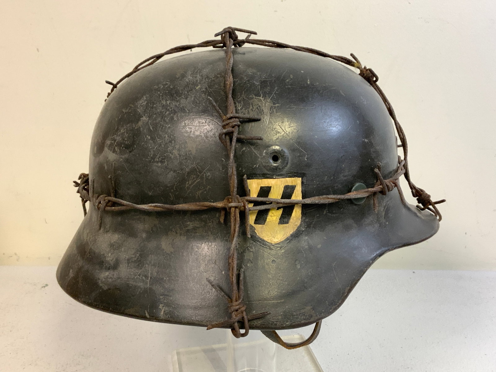 WWII GERMAN DRAMATIC DISPLAY SS COMBAT HELMET WITH BARBED WIRE: WWII GERMAN DRAMATIC DISPLAY SS COMBAT HELMET WITH BARBED WIRE. DOUBLE DECAL WITH SS DECAL APPEARS TO BE HAND PAINTED. LOOKS VERY IMPRESSIVE AND MAKES A GREAT DISPLAY PIECE. THE LINER APPEARS TO BE OR