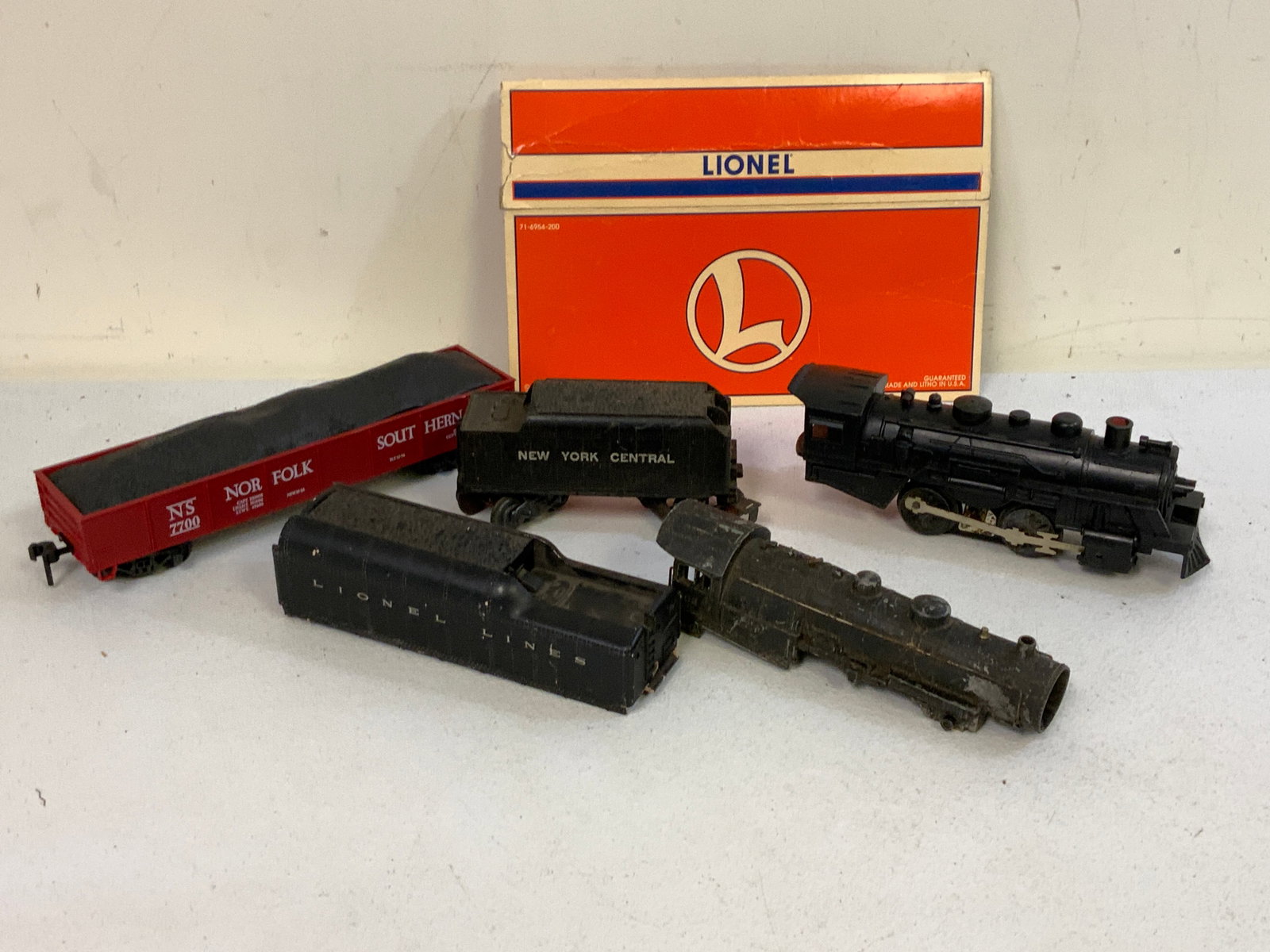 VINTAGE LIONEL TRAIN STEAM LOCOMOTIVE O GAUGE TRAIN CARS LOT: VINTAGE LIONEL TRAIN STEAM LOCOMOTIVE O GAUGE TRAIN CARS AND PARTS LOT. WELL USED. LIONEL DISPLAY BOX ON THE BACKGROUND IS NOT INCLUDED.