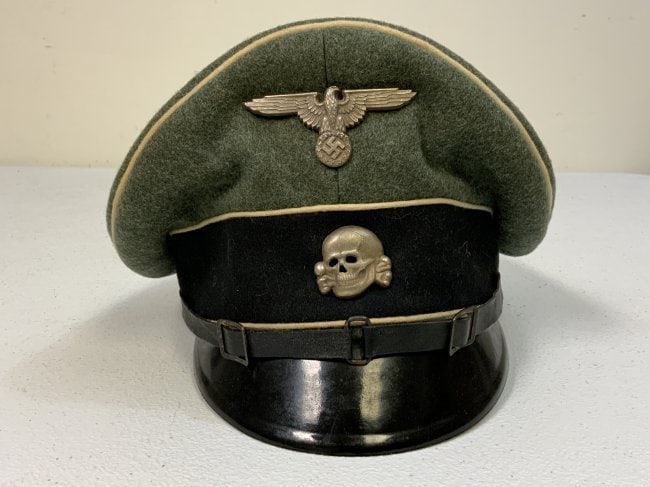 WWII GERMAN WAFFEN SS NCO OFFICER VISOR CAP: WWII GERMAN WAFFEN SS NCO OFFICER VISOR CAP . WELL WORN CONDITION BUT STILL DISPLAYS GREAT SADDLE SHAPE. TORN SWEAT BAND INSIDE. MAKER LOGO VISIBLE ON THE LINING. SIZE ABOUT 56