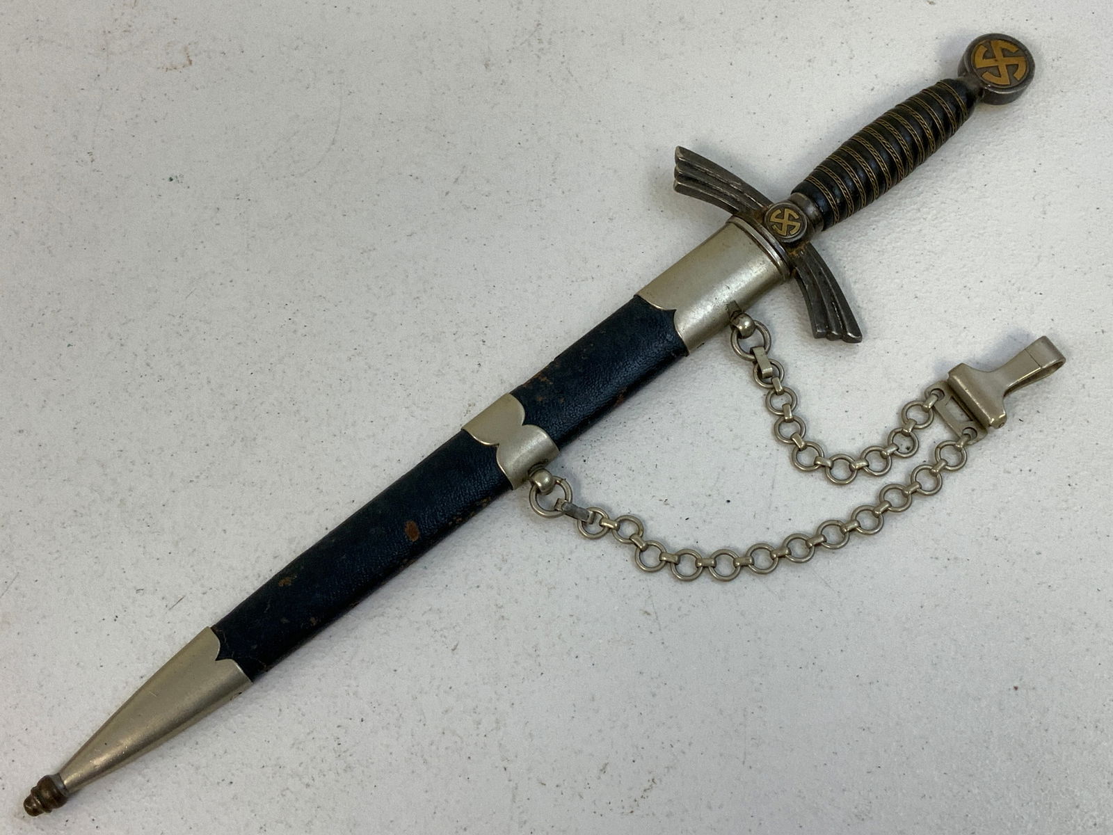 GERMANY THIRD REICH LUFTWAFFE OFFICERS FIRST MODEL DAGGER SMF SOLINGEN: GERMANY THIRD REICH LUFTWAFFE OFFICERS FIRST MODEL DAGGER SMF SOLINGEN. BEUTIFUL BRIGHT BLADE. GILDED SUNWHEEL SWASTIKAS.SOME WEAR TO THE LEATHER COVERED SCABBARD. VERY NICE DAGGER.