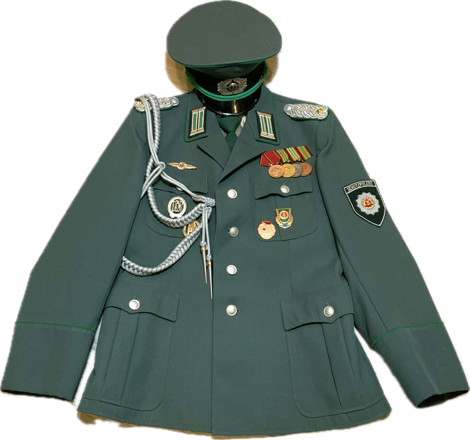 EAST GERMANY DDR SCHUTZPOLIZEI UNIFORM TUNIC AND HAT: EAST GERMANY DDR SCHUTZPOLIZEI UNIFORM TUNIC AND HAT. VERY NICE SET. TUNIC COMPLETE WITH ALL INSIGNIAS AND MEDALS. NICE AND CLEAN. COMES WITH ORIGINAL TIE.