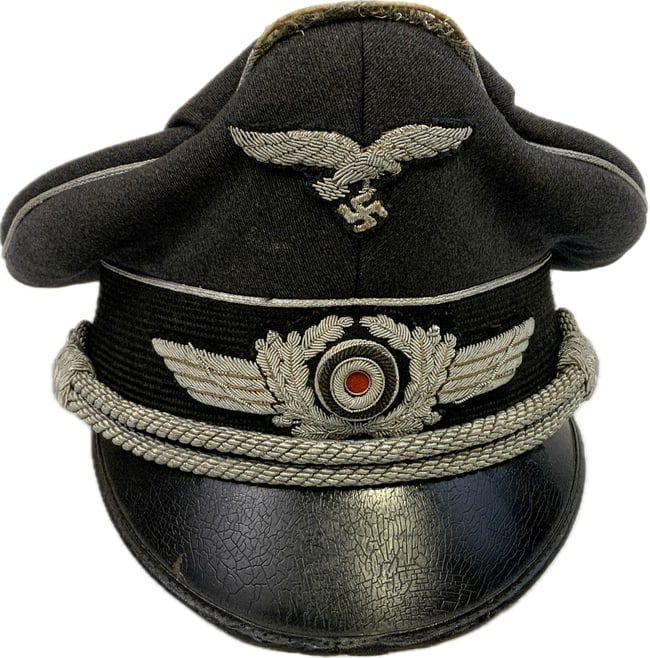 WWII GERMAN LUFTWAFFE OFFICERS VISOR CAP HAT: WWII GERMAN LUFTWAFFE OFFICERS VISOR CAP HAT. WELL WORN EXAMPLE WITH GREAT CHARACTER. HIGH PEACK FORMED BY ORIGINAL OWNER WITH WEAR TO THE SILVER OFFICER GRADE PIPING. VERY NICE HIGH QUALITY SILVER WI