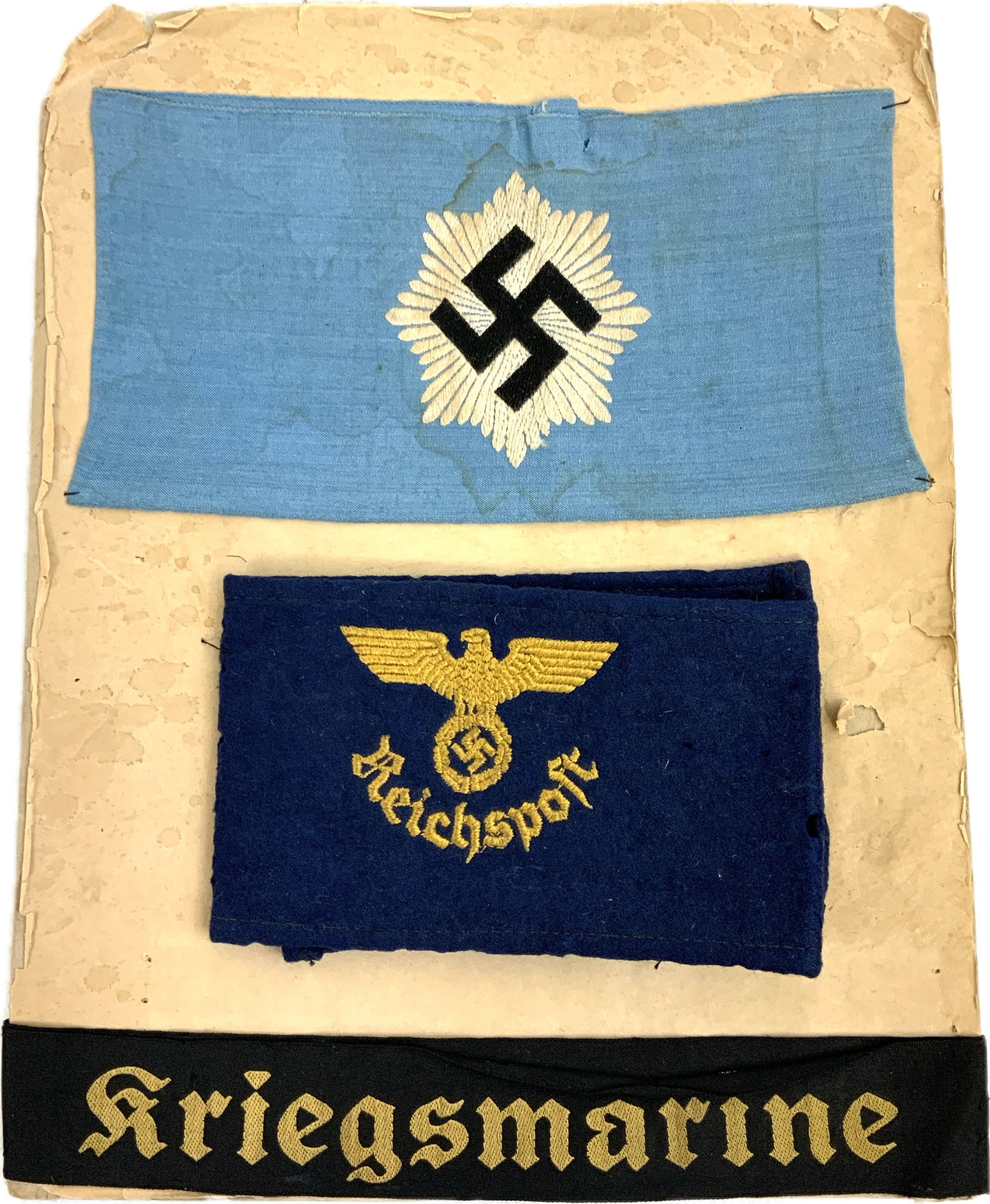 WWII GERMAN ARMBANDS AND NAVY HAT TALLY ON US VETERANS DISPLAY: WWII GERMAN ARMBANDS AND NAVY HAT TALLY ON US VETERANS DISPLAY.LOT OF 3 PIECES MOUNTED BY US VETERAN ON CARDBOARD. NAMED ON THE BACK TO PRT. THOMAS P.MANN.