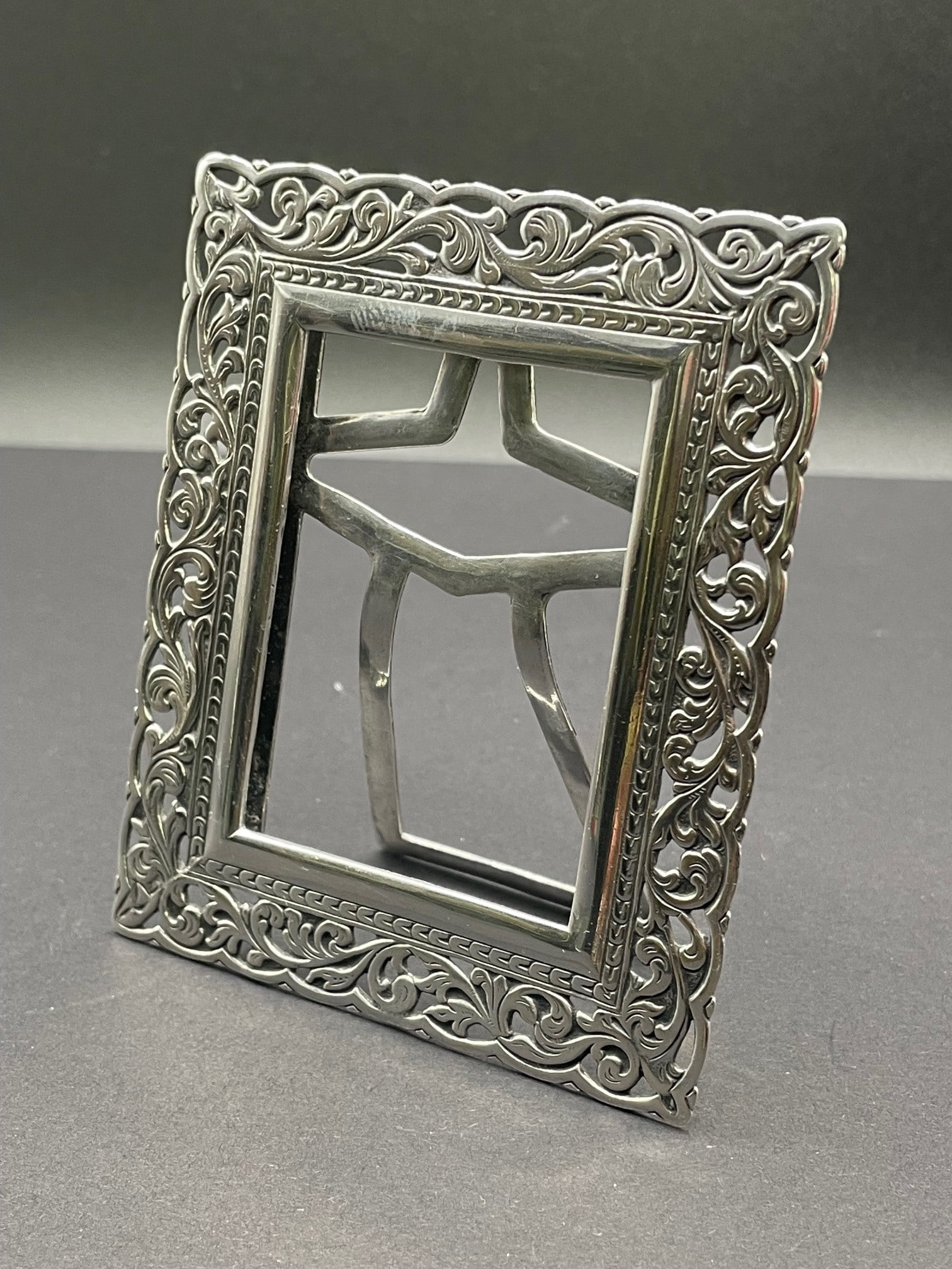 STERLING SILVER ACANTHUS LEAF DESK TOP PICTURE FRAME marked, '925' with hallmarks. DETAILS:: STERLING SILVER ACANTHUS LEAF DESK TOP PICTURE FRAME marked, '925' with hallmarks. DETAILS: - FRAME SIZE: 3-3/8 In. Height x 2-7/8 In. Width. - PICTURE SIZE: 2-1/4 In. Height x 2 In. Width. - WEIGHT: 