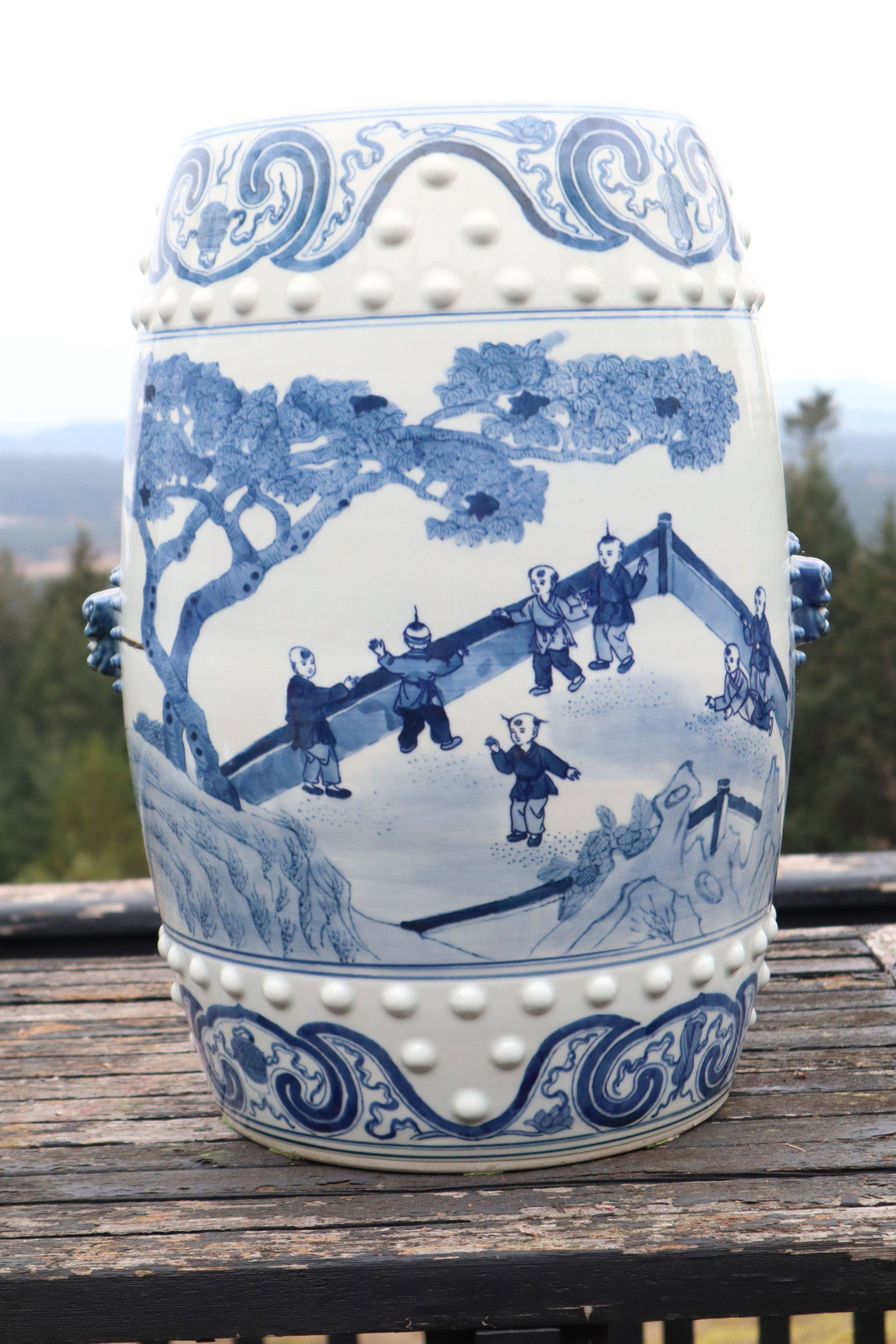 BLUE AND WHITE CHINESE PORCELAIN GARDEN SEAT DECORATED WITH CHILDREN IN GARDEN, BRUSH PAINTED GLAZE: Blue And White Chinese Porcelain Garden Seat, Decorated With Children In Garden, Brush Painted Glaze On Top And All Sides With Molded Accents On Top And Bottom Borders, And Two Molded Foo Dog Face Han