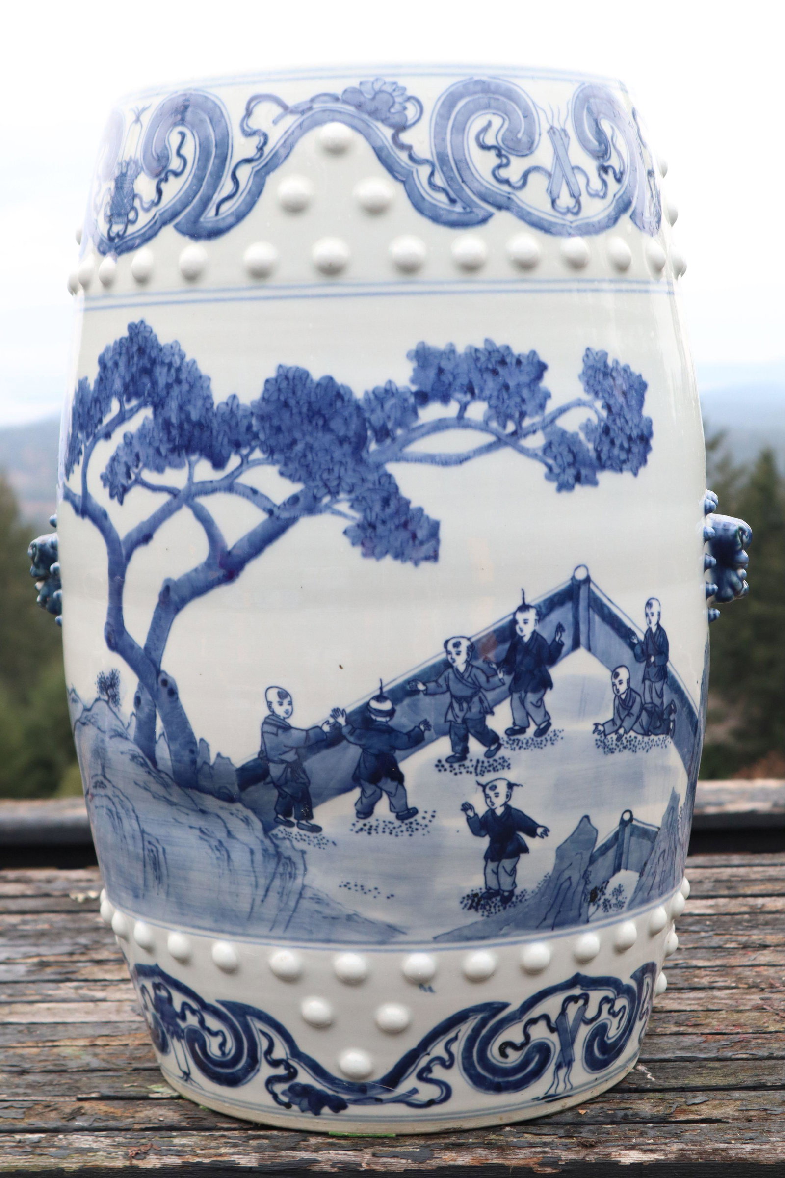 BLUE AND WHITE CHINESE PORCELAIN GARDEN SEAT DECORATED WITH CHILDREN IN GARDEN, BRUSH PAINTED GLAZE: Blue And White Chinese Porcelain Garden Seat, Decorated With Children In Garden, Brush Painted Glaze On Top And All Sides With Molded Accents On Top And Bottom Borders, And Two Molded Foo Dog Face Han