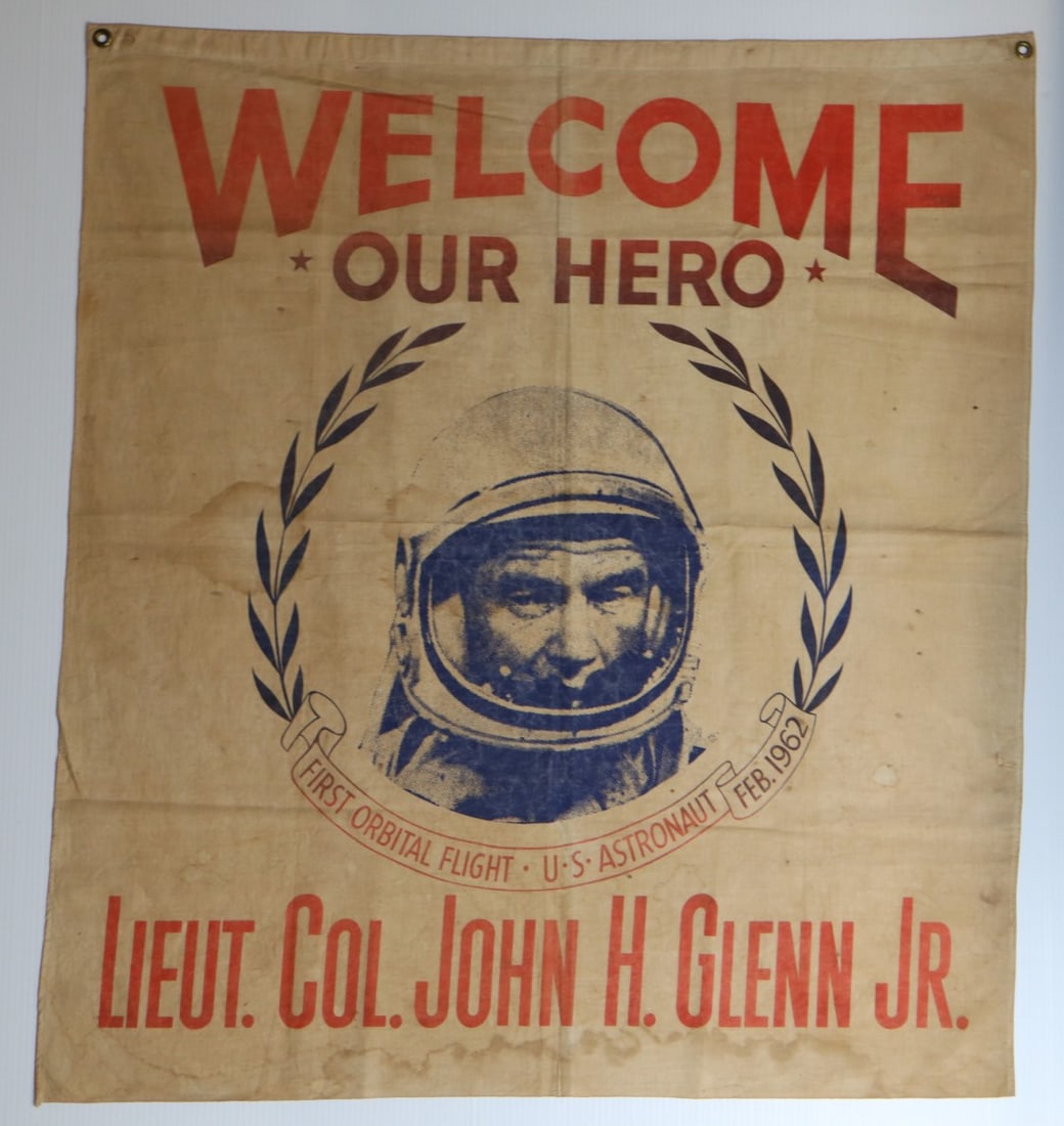 CELEBRATION BANNER FLAG TO HONOR JOHN GLENN JR. AS THE FIRST AMERICAN TO ORBIT THE EARTH, 1962: DESCRIPTION: CELEBRATION BANNER FLAG TO HONOR JOHN GLENN JR. AS THE FIRST AMERICAN TO ORBIT THE EARTH, POSSIBLY DISPLAYED DURING THE 1962 NEW YORK TICKER TAPE PARADE,? "WELCOME OUR HERO LIEUT. COL. JO