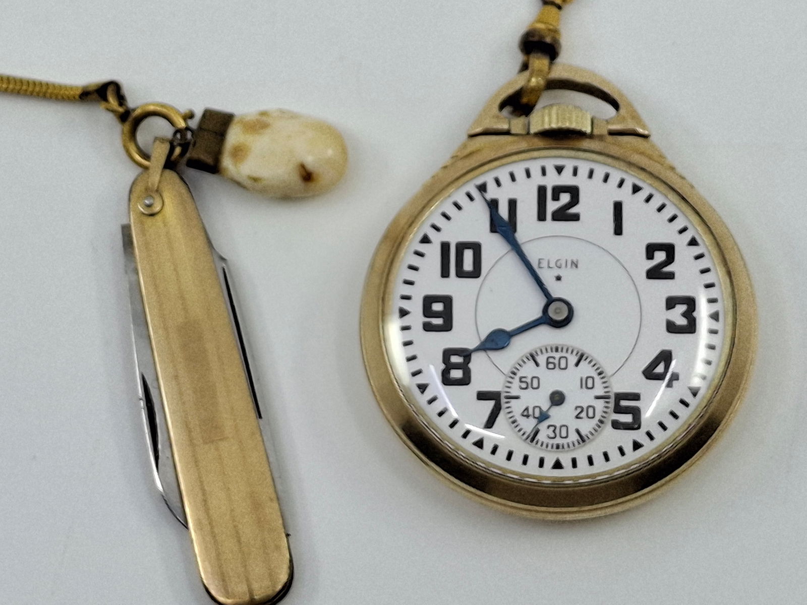 10K GOLD FILLED ELGIN POCKET WATCH AND FOB WITH POCKET KNIFE, FOSSILIZED TOOTH. WATCH HAS 21 JEWELS: DESCRIPTION: 10K GOLD FILLED ELGIN POCKET WATCH AND FOB WITH POCKET KNIFE AND FOSSILIZED TOOTH. WATCH HAS 21 JEWELS, B.W. RAYMOND MOVEMENT #41168727, CASE 50MM, 10K GF, MOVEMENT WORKS, POST NOT ENGAGI