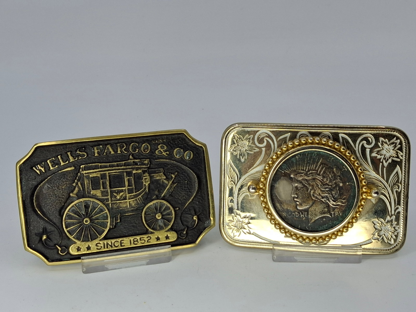 PEACE DOLLAR BELT BUCKLE, AND WELLS FARGO & CO BELT BUCKLE: DESCRIPTION: PEACE DOLLAR BELT BUCKLE, AND WELLS FARGO & CO BELT BUCKLE. CONDITION: Please See Photos For Condition. Condition Is Commensurate With Age And Use. We Aim To Take Additional Photos Of Any