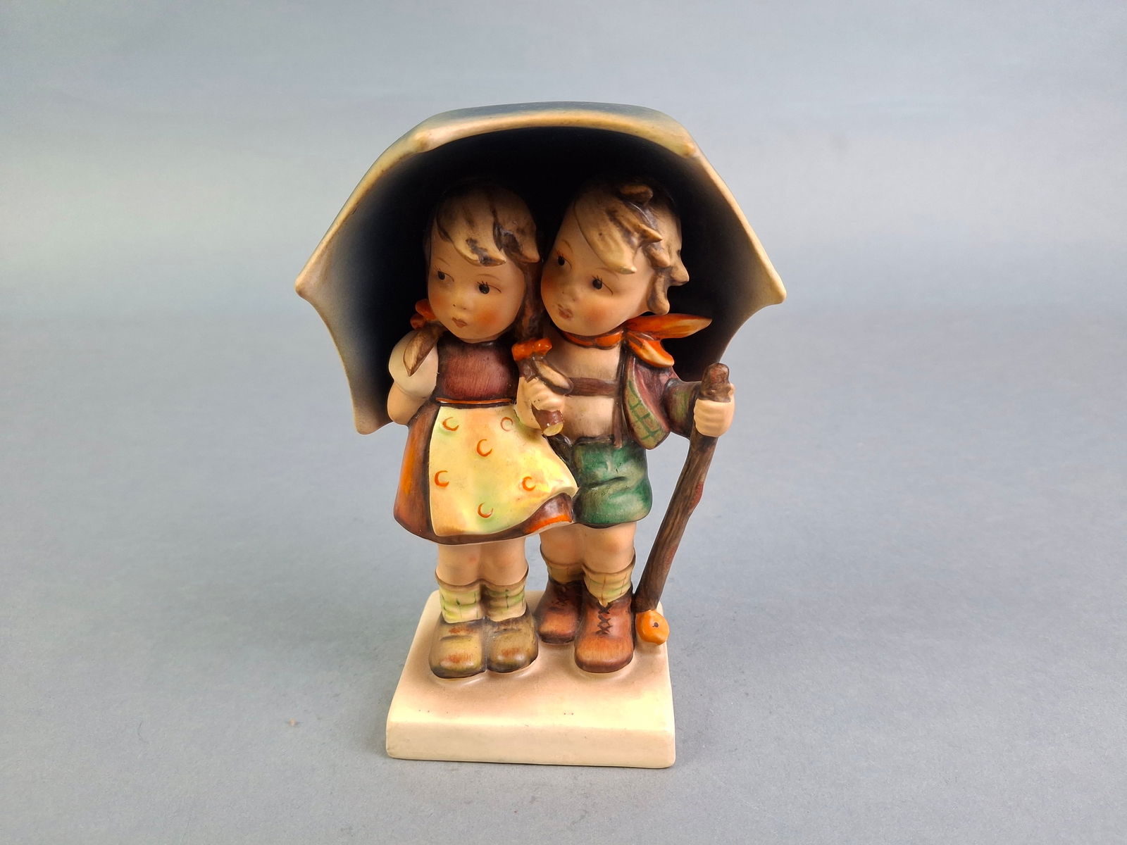 GOEBEL HUMMEL "STORMY WEATHER" PORCELAIN FIGURINE, 6-1/2", HANDLE OF UMBRELLA MISSING.: GOEBEL HUMMEL "STORMY WEATHER" PORCELAIN FIGURINE, 6-1/2", HANDLE OF UMBRELLA MISSING.