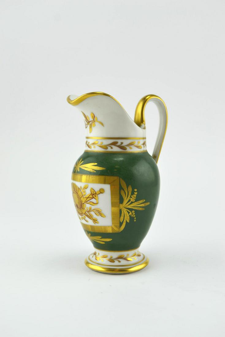 Sevres porcelain jar.: Jarrita en porcelana de Sèvres estilo Imperio pintada a mano sobre fondo verde con detalles en oro, con cartela decorada con motivos militares. Alto 13.5 cm.