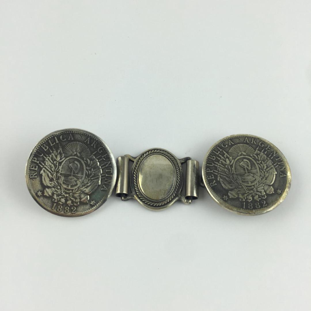 Belt buckle: Argentinean belt buckle in silver decorated with two 1882 coins, marked by the silversmith N. Davan. Rastra argentina en plata decorada con dos monedas de 1882, marcada por el platero N. Davan.