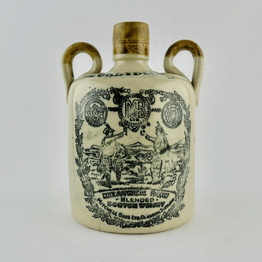 Scotch whisky bottle in stoneware: Scotch whisky bottle in stoneware. "The Greybeard. Heather Dew Blended Scotch Whisky." Mitchell Bros. Ltd. Scotland." Two-tone, with double handle, black stamped mark and Possil maker's incised stamp.
