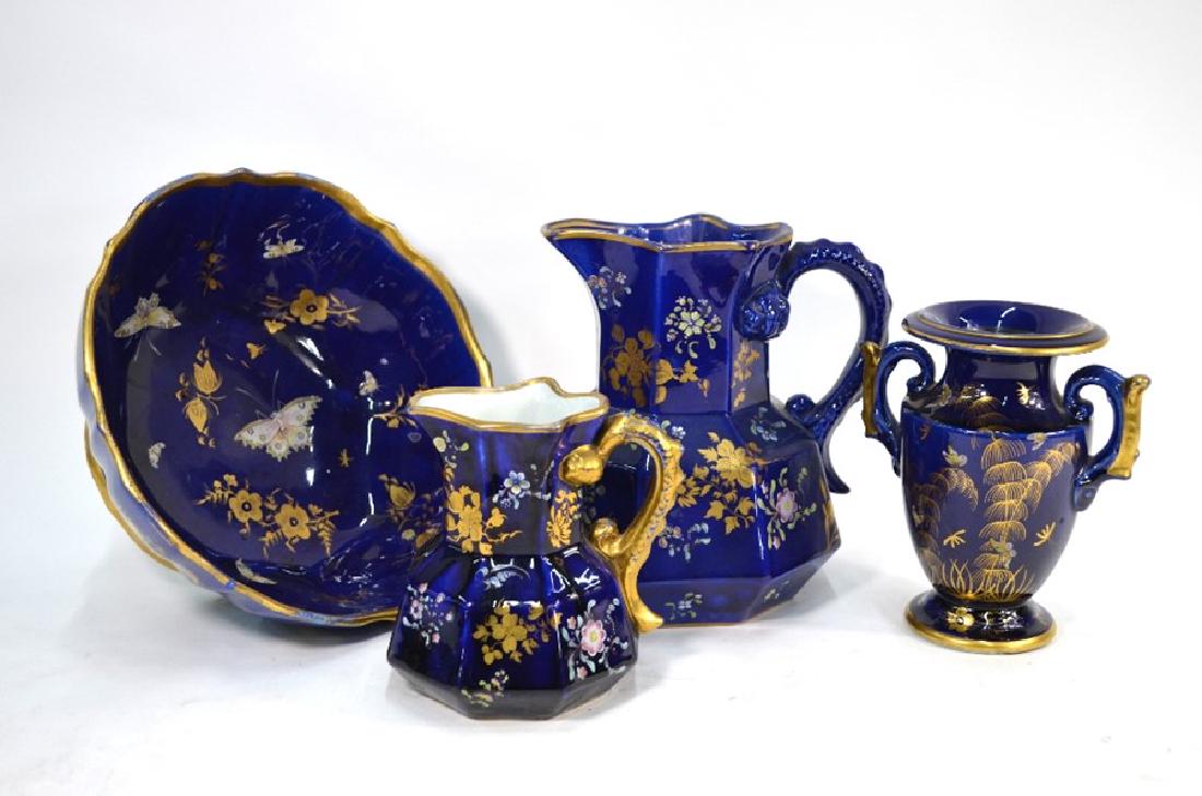 Four Victorian ironstone mazarine blue ground items: Four Victorian ironstone mazarine blue ground items - A fluted bowl decorated with gilded and enamelled flowers and moths, two octagonal jugs decorated with gilded and enamelled floral sprays, 13 and